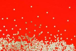 Red backdrop with glitter and silver stars confetti. Festive holiday bright background photo