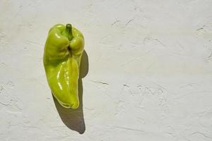 Trendy ugly organic green bell pepper with spots on white backgeound. Hard light. photo