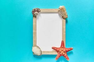 mockup photoframe with sea shels and star fish on blue background. Marine decoration concept photo