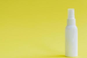 White packaging spray cosmetic plastic bottle on yellow background. Mockup for hair or body care products photo