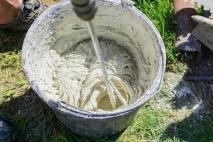 mixing tile adhesive or cement with a power drill for garden repair works photo