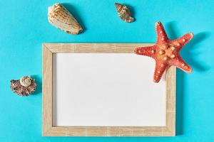mockup photoframe with sea shells and star fish on blue background. Marine and vacation concept photo