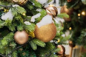 close up of christmas tree decorated with sparkling balls and garland with lights on. Festive background with copy space for your projects photo