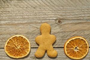 vista superior de rodajas de naranja secas y hombre de pan de jengibre sobre fondo de madera. tarjeta de felicitación navideña festiva con espacio de copia para sus proyectos foto