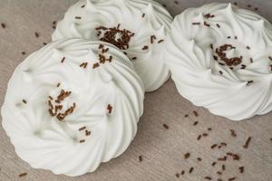 homemade white air meringues and chocolate confectionery decorations on  on parchment paper. photo