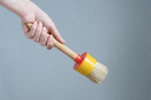 woman holding a big paint brush in her hand fro doing repairs. photo