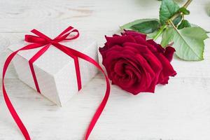 caja de regalo de lunares beige con lazo de cinta roja y hermosas rosas rojas sobre fondo de madera. tarjeta de felicitación para vacaciones. foto