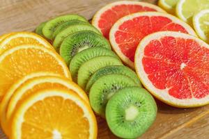 frame with slice of oranges, lemons, kiwi, grapefruit pattern on wooden background. copy space. photo