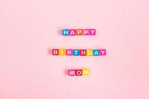 inscripción de feliz cumpleaños mamá hecha de cuentas de cubo de colores con letras. concepto de fondo rosa festivo con espacio de copia