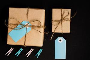 Handcrafted gift boxes wrapped in Craft paper  with blue paper card tag, rope and wooden  clothespins for decoration. photo