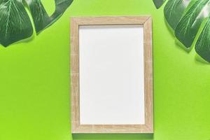 green background with monstera tropical leaves and mock up photo frame