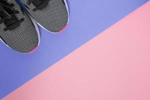 Black and white sneakers with pink sole on ultra violet and pink background. Concept of healthy lifestile and everyday training. Top view with copy space for your project photo