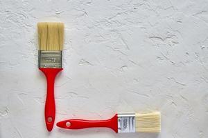 two paintbrushes with red handles on freshly made concrete background. Repairing concept. Top view with copy space photo