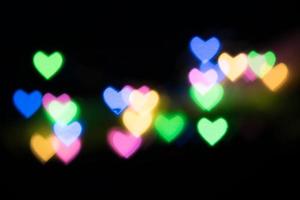 Multicolored hearts bokeh of blue, green, pink and orange colores on black background. Texture for holidays photo