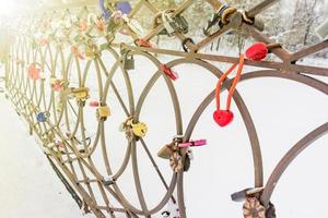 Love padlocks on bridge over the river in a sunny winter day photo