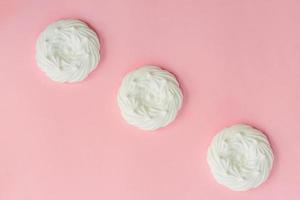 top view of homemade white air meringues on pink background photo