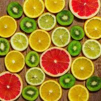 frame with slices of oranges, lemons, kiwi, grapefruit pattern on wooden background. Copy space photo