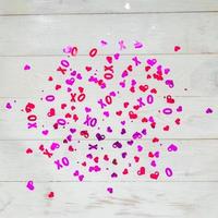 White wooden background with red and purple hearts confetti for Valentine's day. Selective focus.  Festive and holiday concept. photo