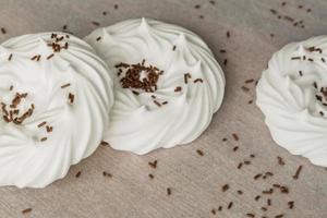 homemade white air meringues and chocolate confectionery decorations on  on parchment paper. photo