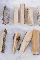 A pile of wooden firewood on the snow prepared for getting warm in  winter. photo