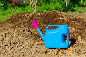 Blue plastic watering can on the ground. Garden equipment photo
