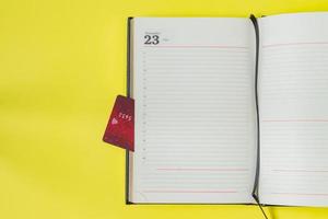 Black friday sale concept. Shopping list in notebook and bank card as bookmark on yellow backgrond photo