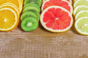 frame with slice of oranges, lemons, kiwi, grapefruit pattern on wooden background. copy space. photo