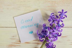 etiqueta de papel de buenos días y flor de jacinto púrpura en la mesa de madera foto