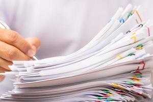 Man in a white shirt sign contract agreement documents in Stack of Group report papers. photo