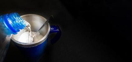 verter agua de la botella en la taza sobre fondo negro foto