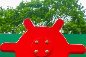 An element of a children's swing. steering wheel . An outdoor colorful playground next to the house. A summer day. Children's playground with rubber floor covering. photo