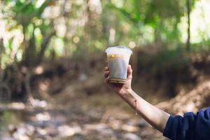 woman holding iced coffee in calm nature photo