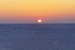 Natural backdrop with sunset over the frozen sea photo