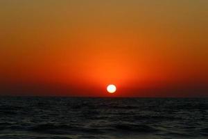 el sol se pone por debajo del horizonte en el mar mediterráneo en el norte de israel. foto