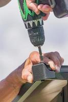 electric screwdriver in males hand. Worker with a hand tool assembling metal construction photo