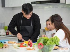 Family father mother girl food cooking eat healthy vegetable salad fruit lunch dinner happy smile enjoy fun lifestyle holiday indoor kitchen home mom and dad love hug son  together parent photo