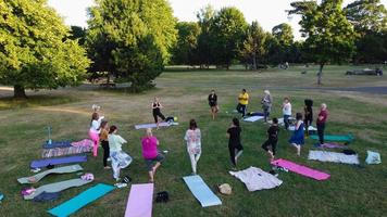 Group of Women Exercising Yoga Together in the Public Park at Sunset of Hot Summer, Aerial High Angle View of Wardown Park Luton England UK photo