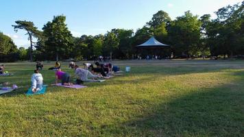 Group of Women Exercising Yoga Together in the Public Park at Sunset of Hot Summer, Aerial High Angle View of Wardown Park Luton England UK photo