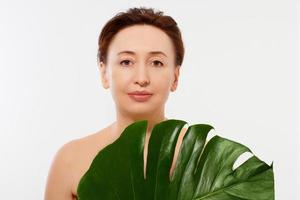 Beauty middle age woman macro face portrait. Spa and anti aging concept and leaf Isolated on white background. Plastic surgery and collagen face injections.Wrinkles and menopause. Mock up. Copy space. photo