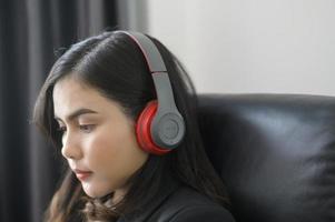 Young relaxing business woman using smartphone and listening to music in modern office. photo