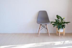 sillas grises y plantas verdes en el piso de madera en una habitación mínima. foto