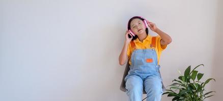 la niña feliz sentada en una silla escuchando música en una habitación mínima en casa. foto