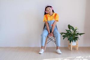 The happy girl sitting on a chair listening to music in minimal room at home. photo