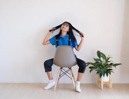 la chica sentada en la silla gris con planta verde en una habitación mínima. foto