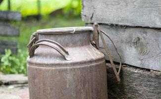 One old rusty metal can in the countryside. Container for transporting liquids, milk or liquid fuels with multiple handles. Milk bank of a cylindrical form with a wide mouth. Bottle with sealed cap. photo