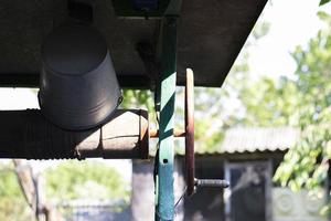 A well with a bucket in a European village. Sunny day. Metal bucket for a water well. Detail of a well with a tin bucket in the countryside. Decorating the garden with vintage items. photo