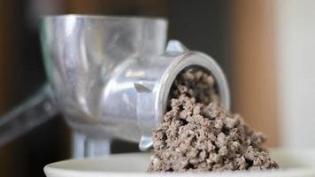 Minced meat in a manual mechanical meat grinder. Fresh boiled meat is ground with an old metal meat grinder, close-up in the kitchen. photo