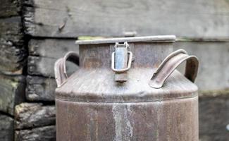 One old rusty metal can in the countryside. Container for transporting liquids, milk or liquid fuels with multiple handles. Milk bank of a cylindrical form with a wide mouth. Bottle with sealed cap. photo