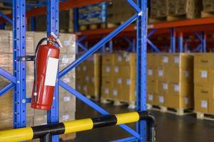 Fire extinguisher on shelf of cardboard boxes in modern warehouse. photo