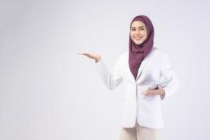 Beautiful muslim business woman wearing white suit with hijab holding tablet in studio photo